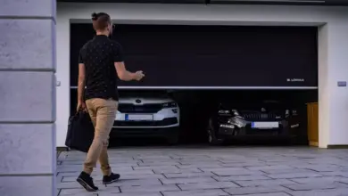 Muž otevírá dvoudveřovou garáž s dvěma auty uvnitř.