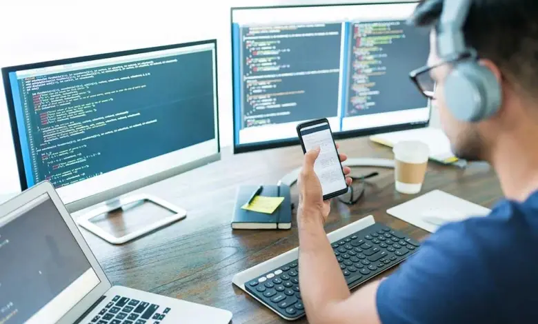 Muž pracuje na kódu u počítače s více monitory.