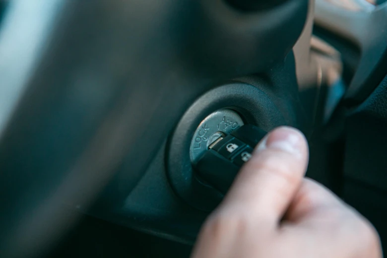 Ruka otáčí klíč v zapalování automobilu při pokusu o start.