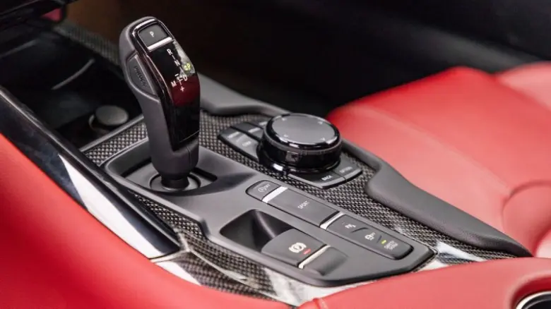 Interiér automobilu s pákou převodovky na karbonovém povrchu.