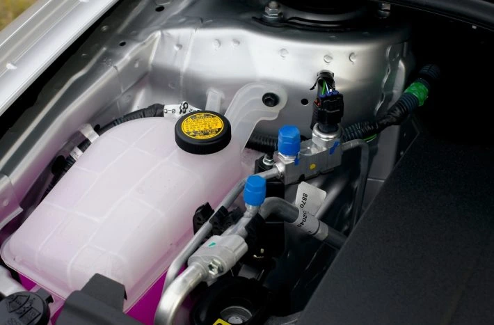 Nádoba na chladicí kapalinu s hadicemi v motorovém prostoru.