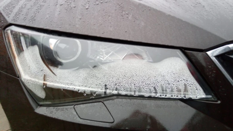 Světlomet pokrytý pěnou při čištění zevnitř vozidla.