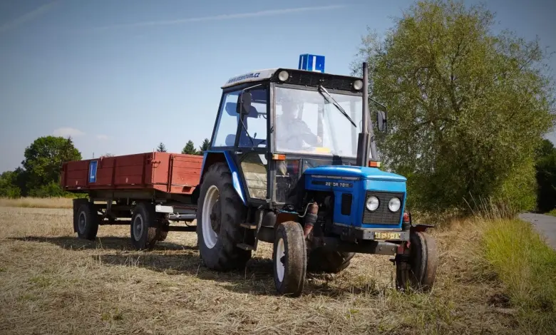 Modrý traktor s přívězem na poli pro ilustraci výcviku.