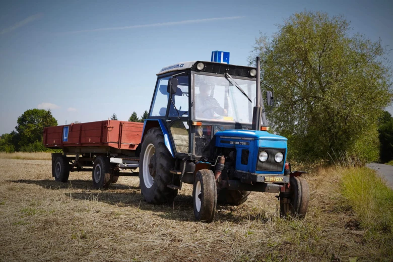 Modrý traktor s přívězem na poli pro ilustraci výcviku.