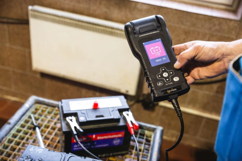 Testování autobaterie připojenou k diagnostickému zařízení v dílně.