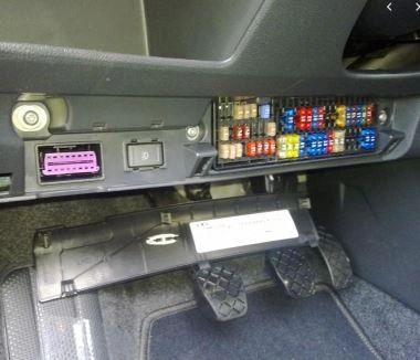 Otevřený pojistkový box v interiéru automobilu s barevnými pojistkami.