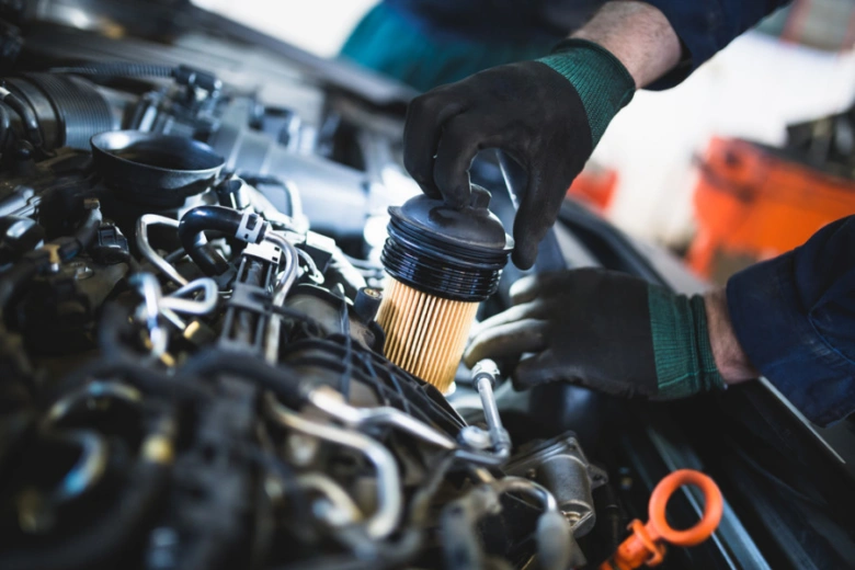 Mechanik mění olejový filtr v motoru automobilu.