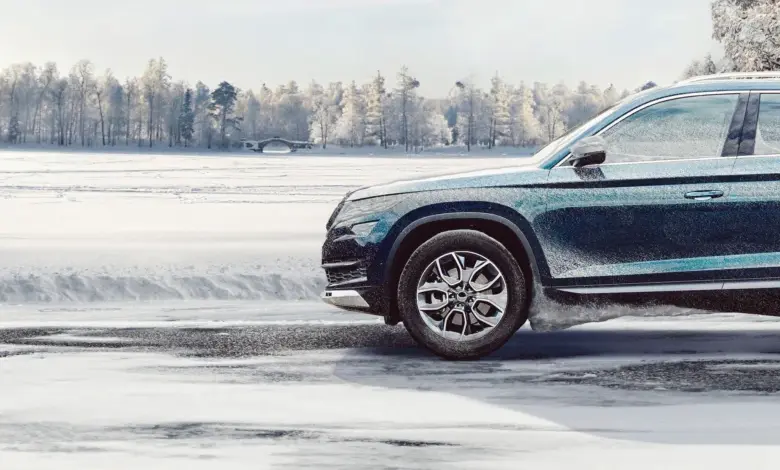 Tmavý automobil jede po sněhu s zimními pneumatikami.