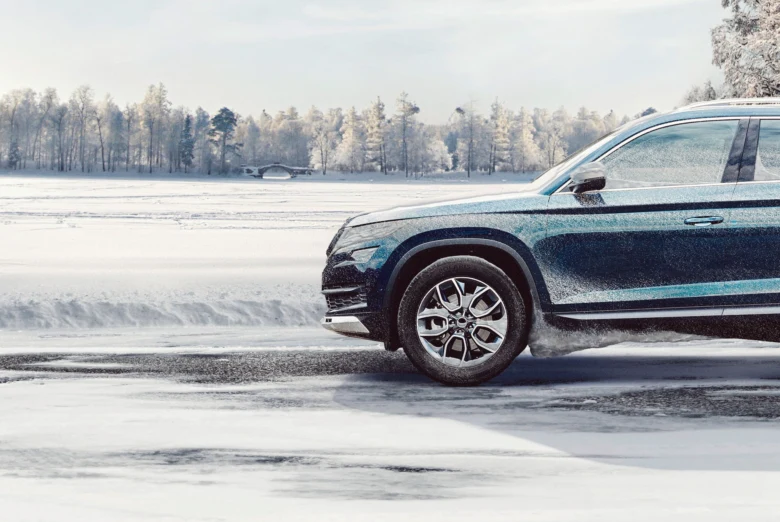 Tmavý automobil jede po sněhu s zimními pneumatikami.