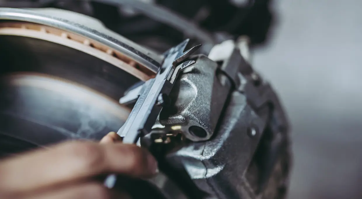 Mechanik měří tloušťku brzdových destiček na automobilu.