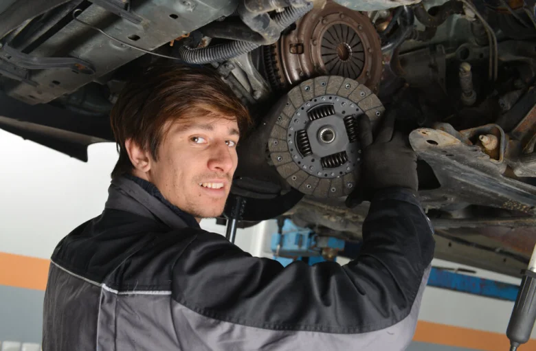 Mechanik montuje automobilovou spojku pod vozidlem.