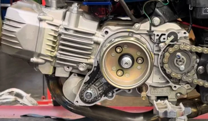 Otevřený motor motocyklu s viditelnými řemeny a ozubenými koly.