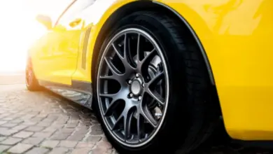 Žluté sportovní auto s detailním záběrem na kovové kolo.