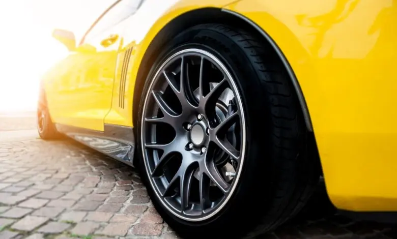 Žluté sportovní auto s detailním záběrem na kovové kolo.