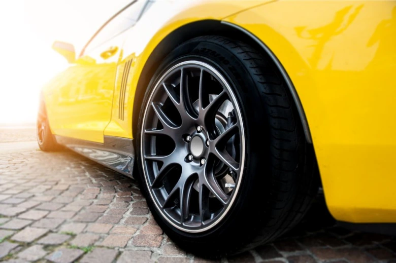 Žluté sportovní auto s detailním záběrem na kovové kolo.