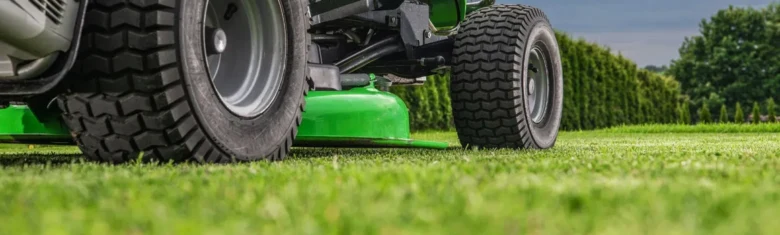 Zelený traktor na trávníku v exteriéru.