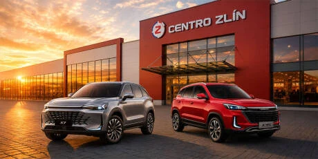 Dva automobily před prodejní budovou Centro Zlín při západu slunce.