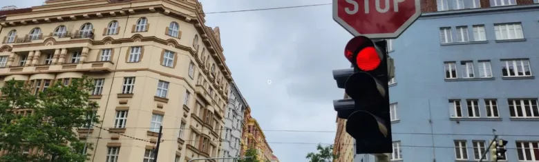 Červená světla na semaforu s dopravní značkou STOP mezi budovami