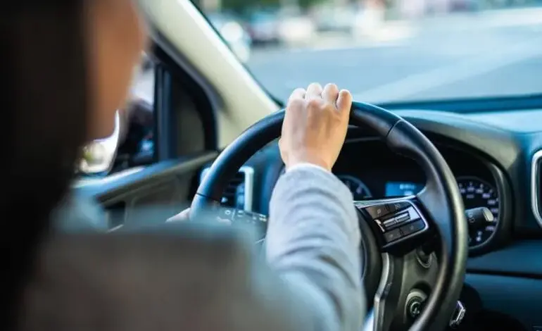 Ruce řidiče na volantu v interiéru automobilu