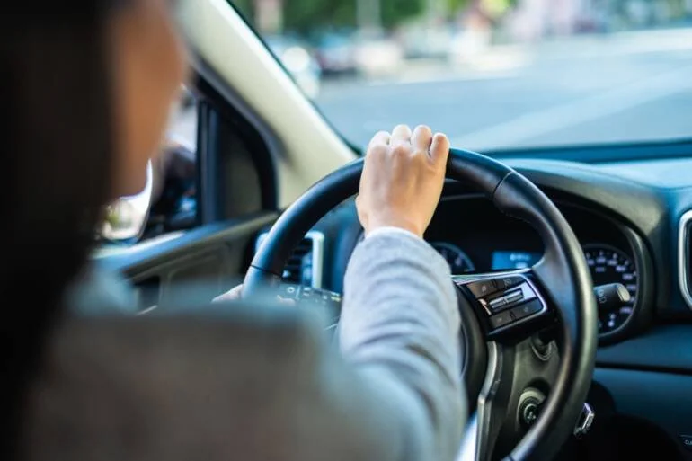 Ruce řidiče na volantu v interiéru automobilu