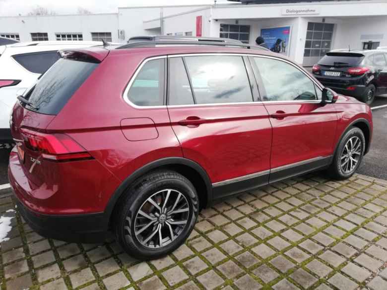 Červený VW Tiguan zaparkovaný před prodejnou.