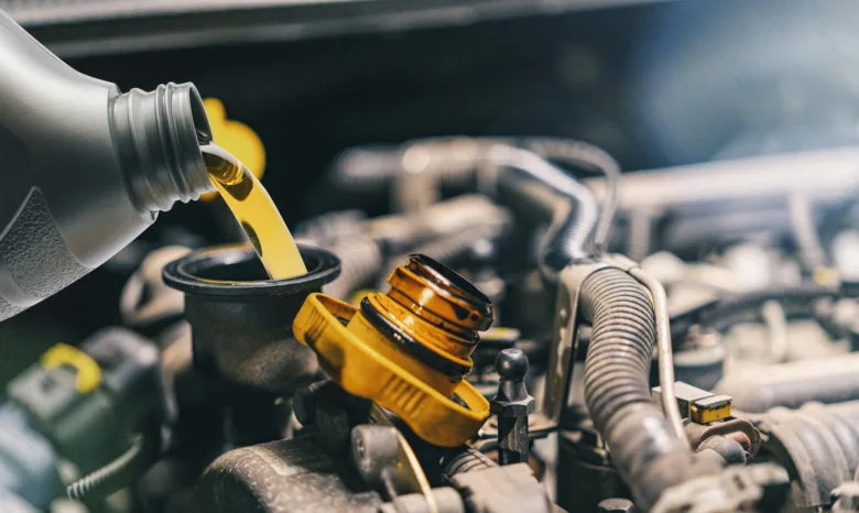 Zelený olej se nalévá do otvoru pro výměnu oleje v automobilovém motoru.
