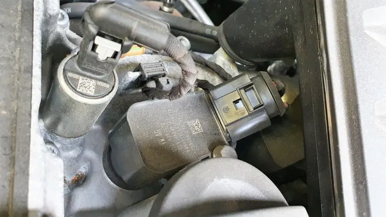 Zapalovací cívka s konektorem v motorovém prostoru automobilu.