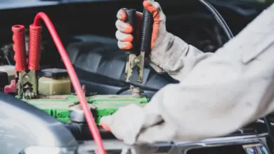 Mechanik připojuje kabely k vybité automobilové baterii.