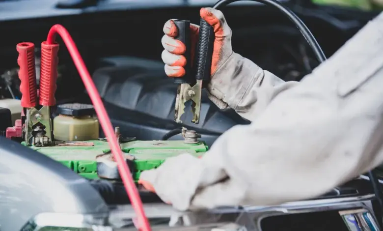 Mechanik připojuje kabely k vybité automobilové baterii.