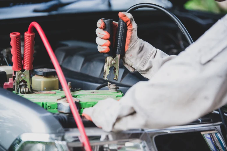 Mechanik připojuje kabely k vybité automobilové baterii.