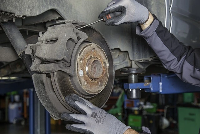 Mechanik opravuje brzdný systém auta pomocí šroubováku.