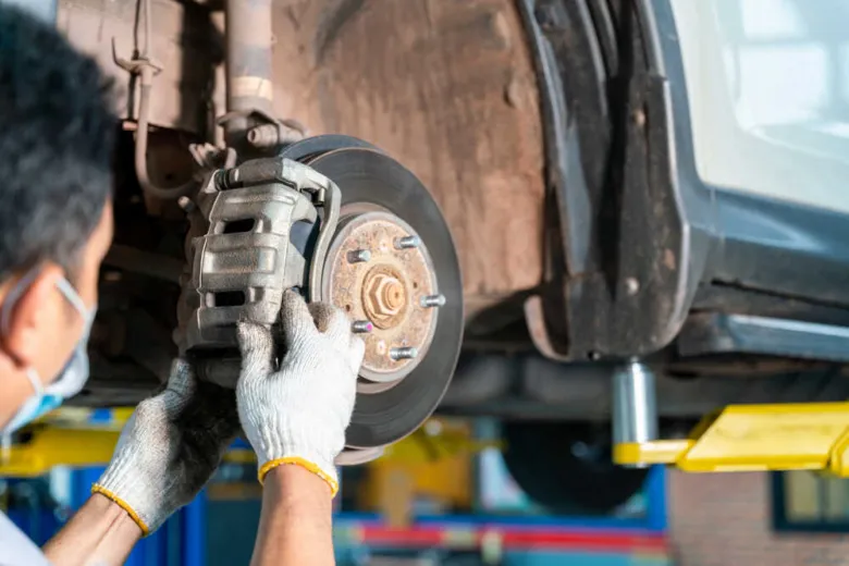 Mechanik opravuje brzdy auta na zvedáku