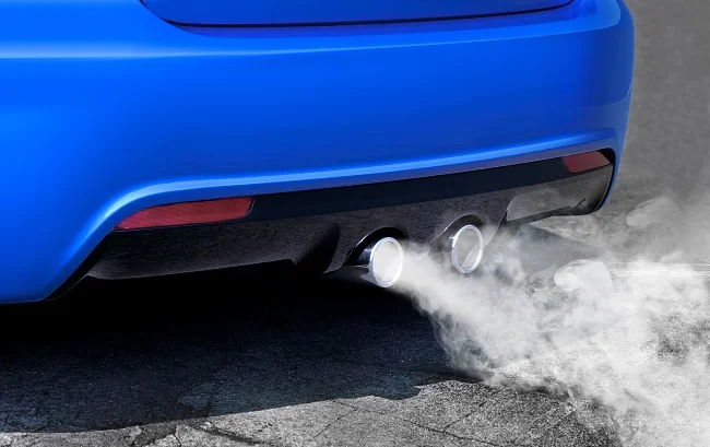 Modré auto kouří z výfuku při rychlém zrychlení.