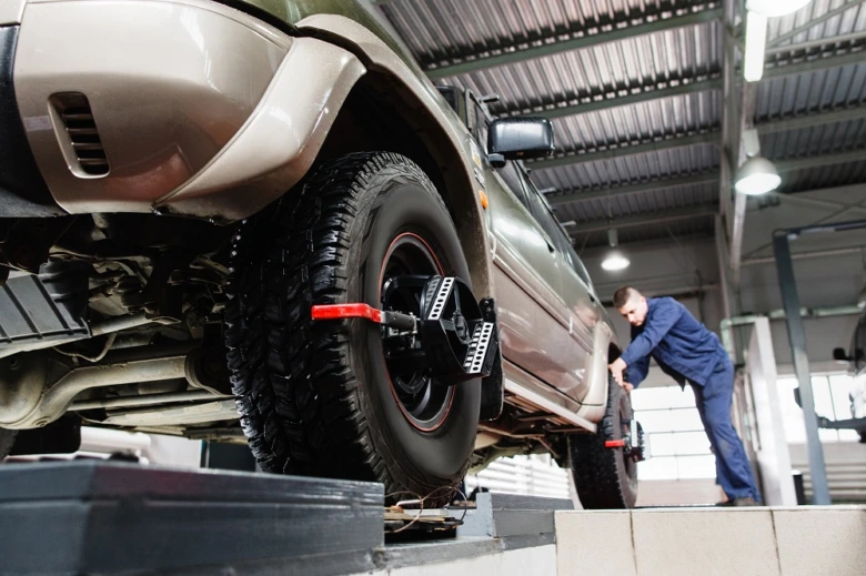 Mechanik upravuje úhly seřízení kol pomocí specializovaného zařízení v dílně.