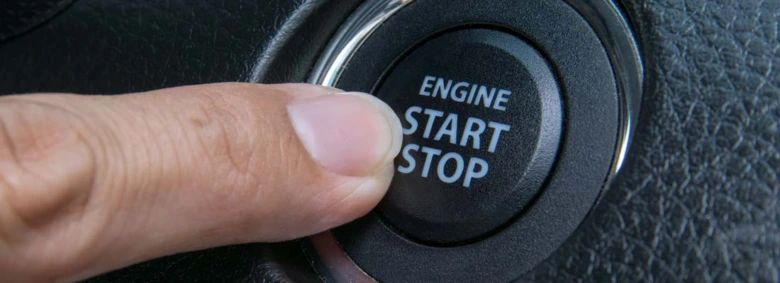 Prst tlačí na tlačidlo pro zapnutí motoru v autě.