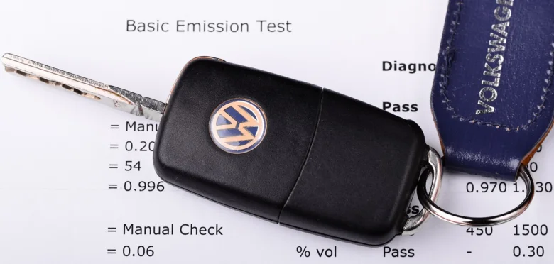 Černý klíč od Volkswagenu s modrým štítkem na papíru.