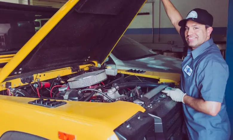 Mechanik opravuje motor vozu v dílně.