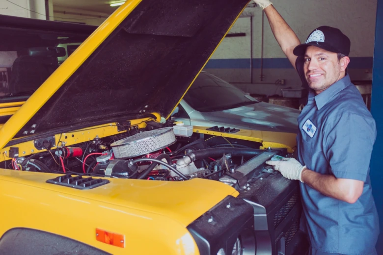 Mechanik u otevřeného motoru žlutého auta v dílně