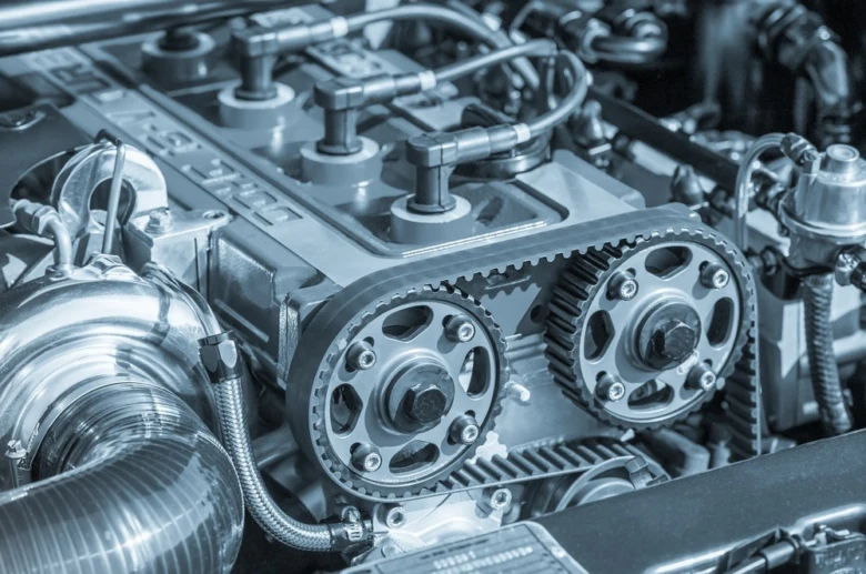 Detail motoru ukazující řemenový systém pro časování ventilů.