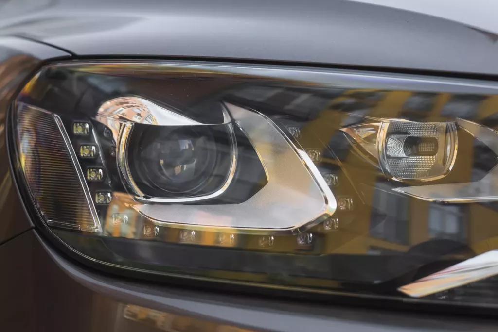 Blízký pohled na světlomet automobilu s detaily pro výměnu žárovky.