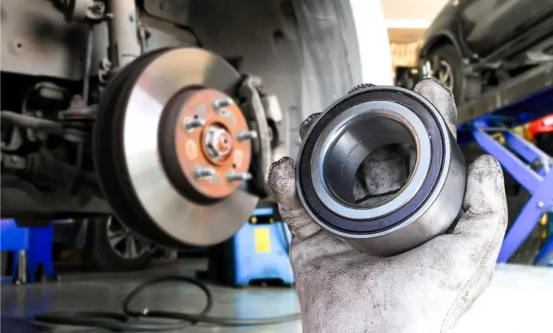 Mechanik drží poškozené ložisko kola s viditelnými známkami opotřebení.