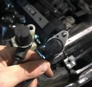 Porovnání dvou snímačů vačkového hřídele v ruce nad motorem.