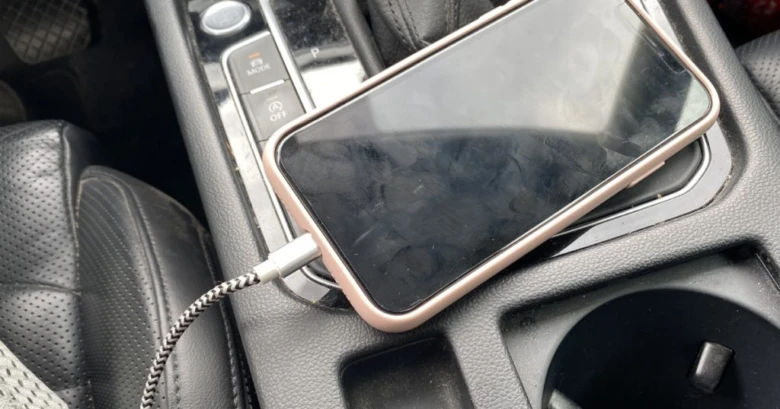 Smartphone připojený k USB portu v autě pro nabíjení.
