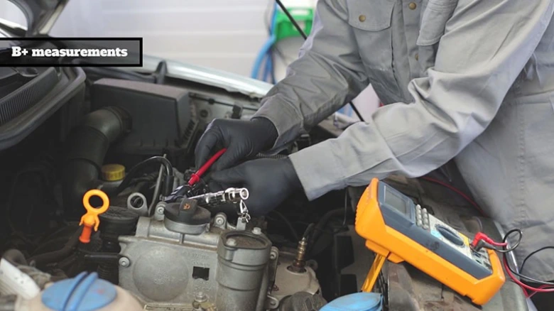 Mechanik měří napětí v motoru multimetrem při diagnostice.