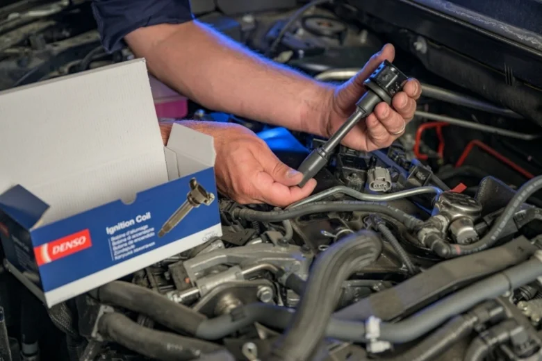 Mechanik montuje nový zapalovací cívku do motoru.