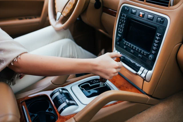 Ruka řidiče přepíná převody v manuální nebo automatové převodovce.