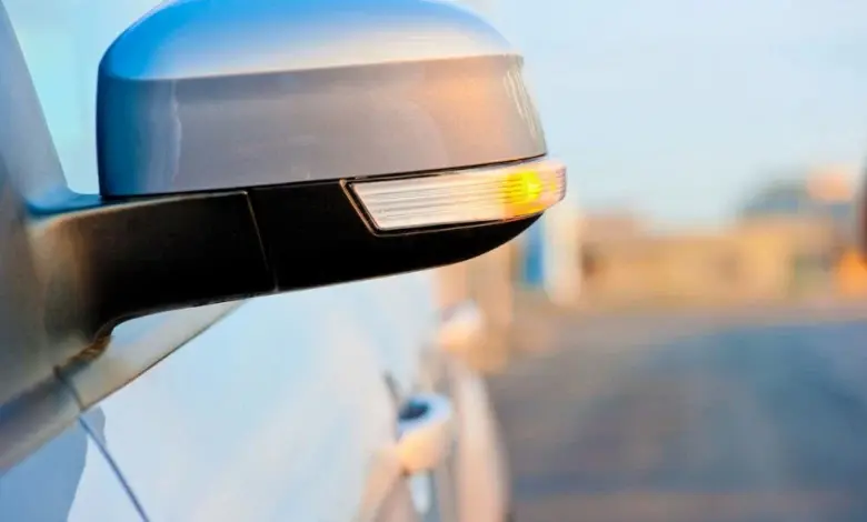 Zapnutý ukazatel směru na bočním zrcátku automobilu.