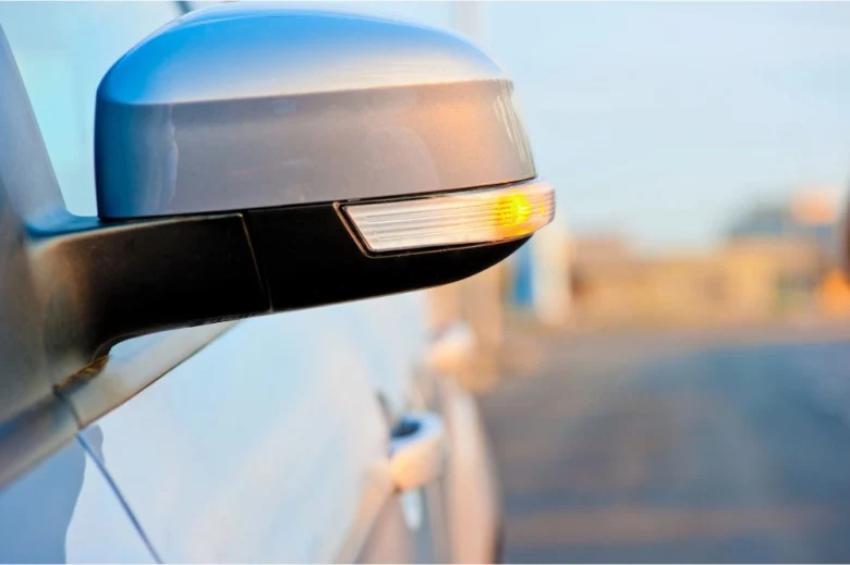 Zapnutý ukazatel směru na bočním zrcátku automobilu.