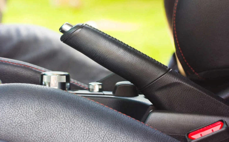 Blízký záběr na ruční brzdu v interiéru automobilu.