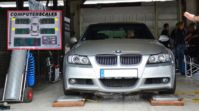 Stříbrný BMW na váhách pro měření hmotnosti vozidla.